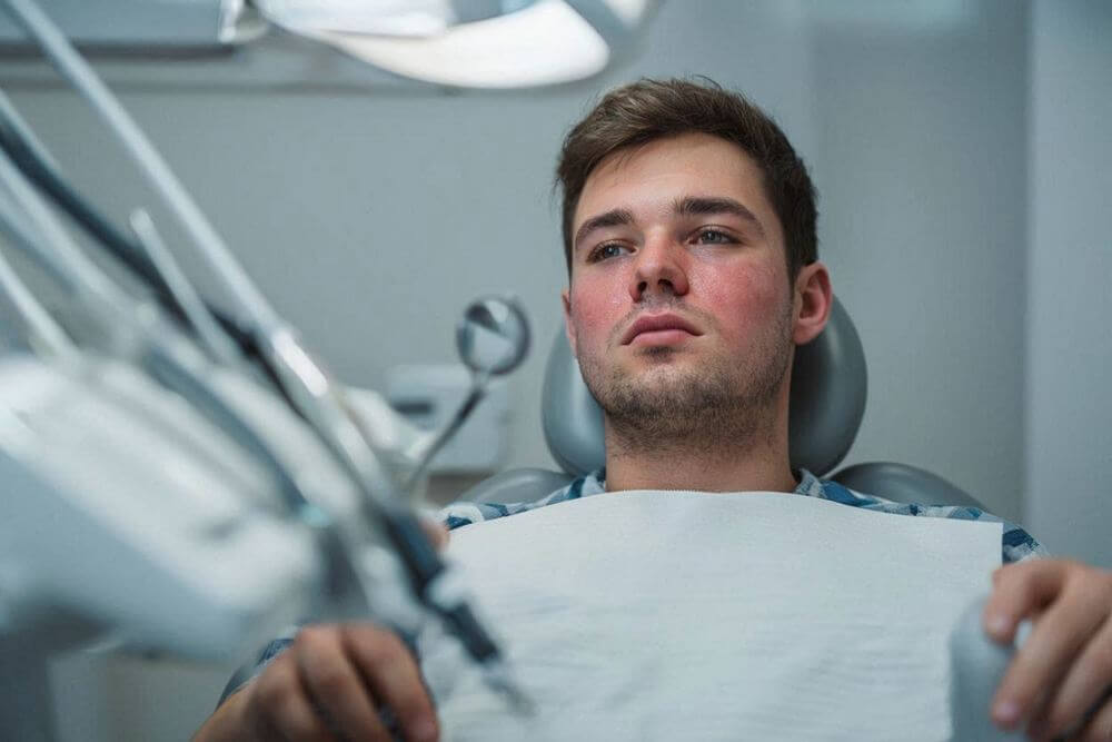 Мужчина с простудой в кресле стоматолога