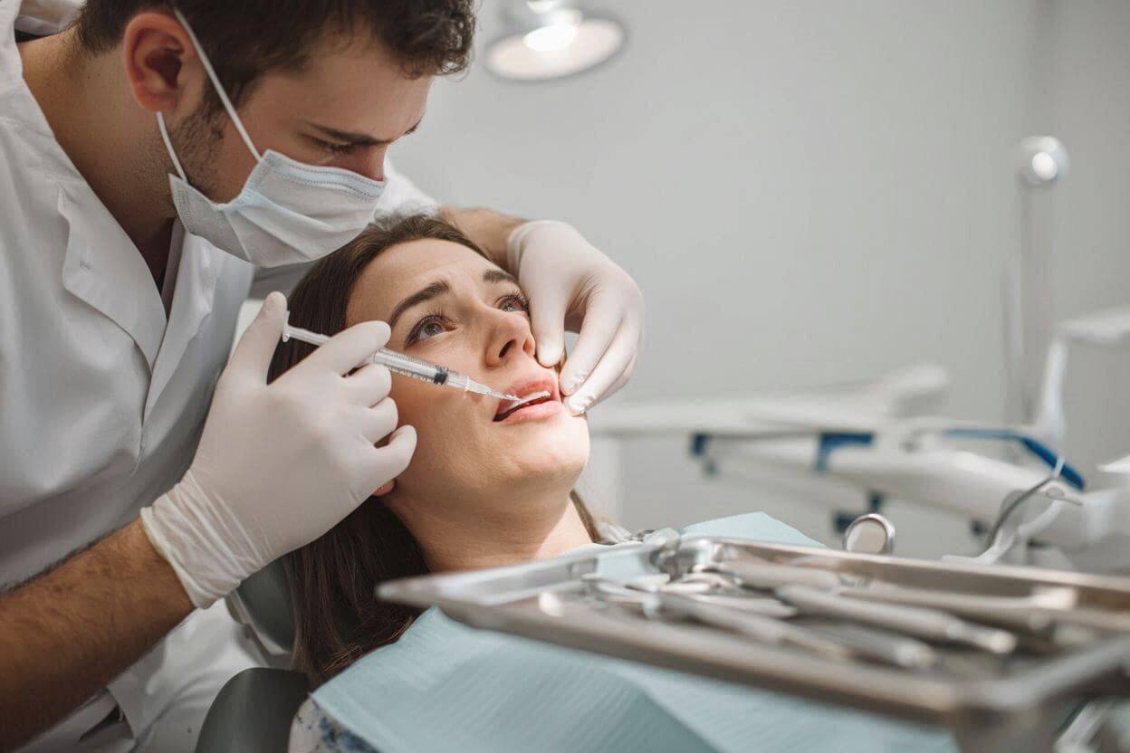 Стоматолог делает укол анестезии женщине